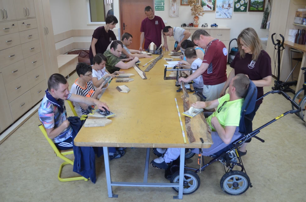 Niepełnosprawne osoby siędzace wspólnie przy stole w pracowni technicznej