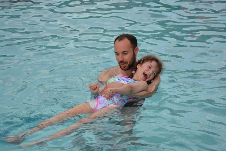 Trener pływania uczy pływać małą dziewczynkę
